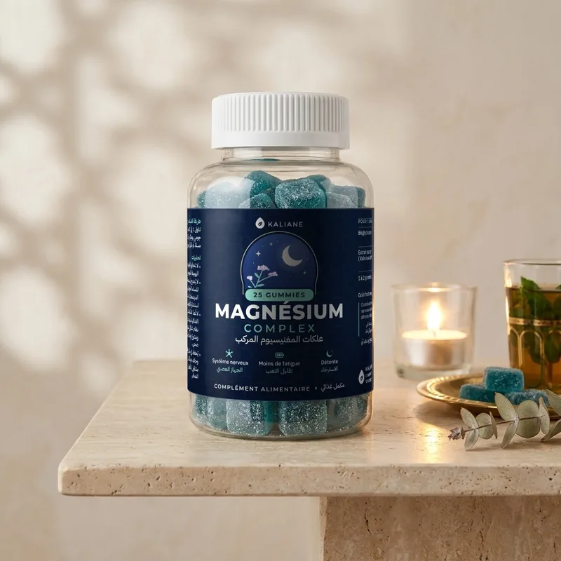 Gummies au magnésium Kaliane sur une table en travertin, avec une bougie allumée et un verre de thé à la menthe